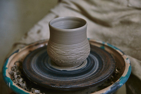 Selective focus of clay pot on pottery wheel at workshopの写真素材