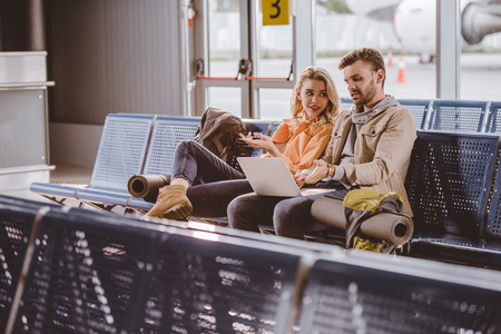 Young couple using laptop and waiting for flight in airport terminalの写真素材