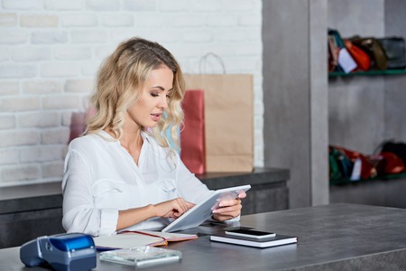 Beautiful young woman using digital tablet while working in shop