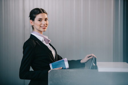 Young female worker smiling at camera while working at check-in desk in airportの写真素材