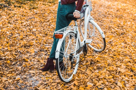 Cropped image of stylish woman posing near bicycle in autumnal forestの写真素材