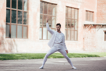 Handsome elegant young man dancing on urban city street
