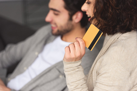 Girlfriend holding credit card and looking away at homeの写真素材