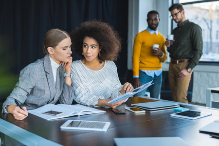 Multicultural businesswomen looking at documents in office