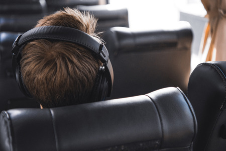 Rear view of male tourist in headphones listening music during trip on travel busの写真素材