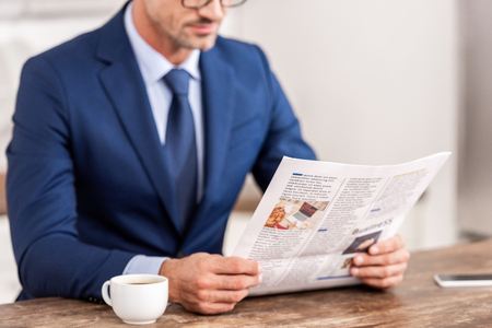 Cropped shot of businessman in suit reading newspaper at morningの写真素材