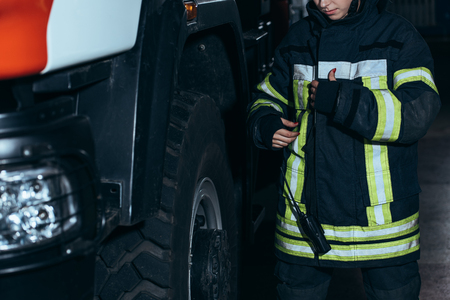 Cropped shot of female firefighter in protective uniform with portable radio set at fire departmentの写真素材