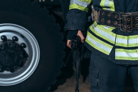 Partial view of firefighter with portable radio set at fire station