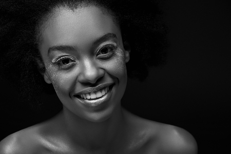 Black and white photo of cheerful African American woman isolated on black backgroundの写真素材
