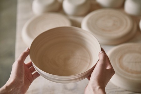 Cropped image of woman holding ceramic dish at pottery studio