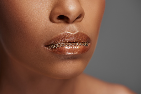 Cropped shot of African American woman with chain on lips isolated on grey backgroundの写真素材