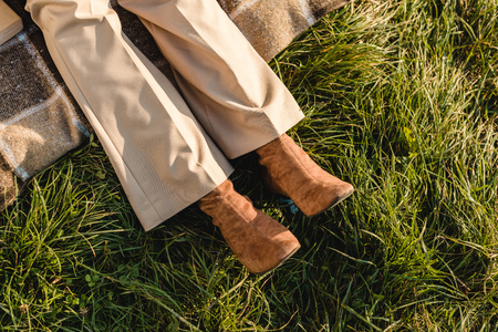 Low section of female legs in suede brown shoes on grass outdoors