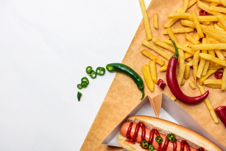 Top view of spicy hot dog with fries on parchment paper isolated on white backgroundの写真素材