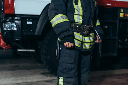 Partial view of firefighter in protective fireproof uniform standing at fire departmentの写真素材