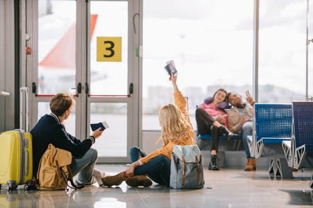 Young travelers with passports and boarding passes greeting each other in airport terminalの写真素材