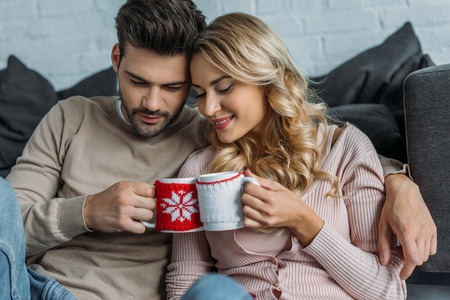 Couple clinking with cups of cappuccino at home, Christmas conceptの写真素材
