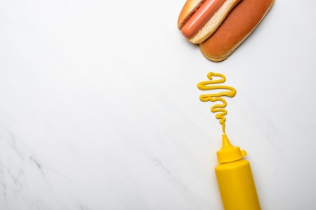 Top view of delicious hot dog with mustard on white marble surfaceの写真素材