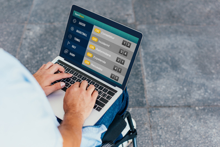 Cropped image of man in wheelchair using laptop with sportbets appliance on streetの写真素材