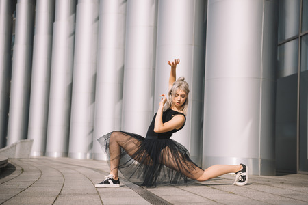 Beautiful young ballerina in black skirt dancing on streetの写真素材