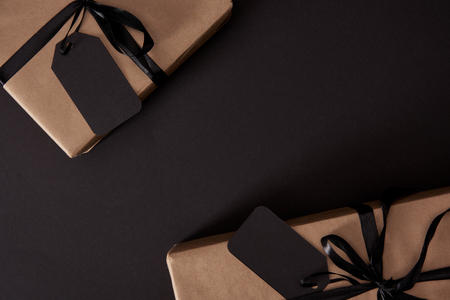 Top view of craft wrapped gifts with black tags on black surface, black Friday conceptの写真素材
