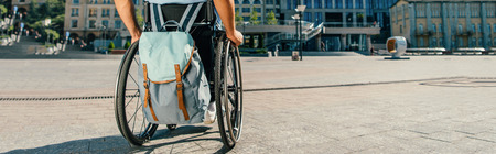 Cropped panoramic view of man using wheelchair with bag on streetの写真素材