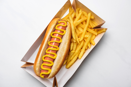 Top view of tasty hot dog with fries in cardboard tray on white backgroundの写真素材