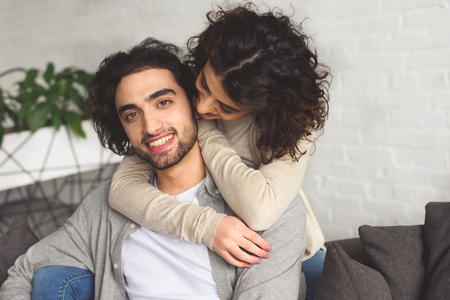 Smiling affectionate couple hugging at homeの写真素材