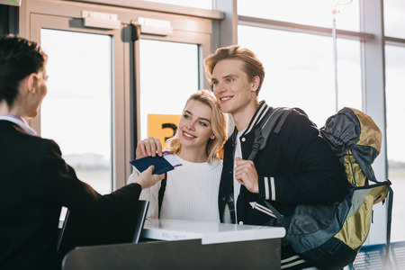 Happy young couple at check-in desk in airportの写真素材