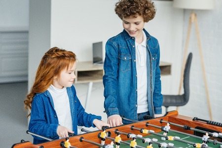 Cute children playing table football togetherの写真素材