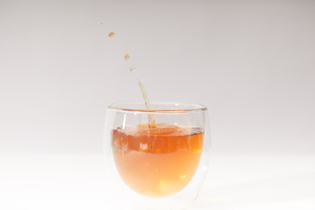 Close-up view of pouring fresh hot tea in glass cup on grey backgroundの写真素材