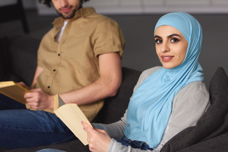Cropped image of Muslim couple sitting with books at homeの写真素材