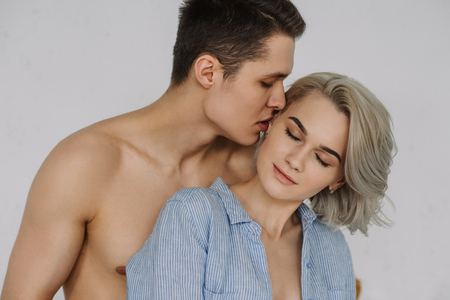 Seductive boyfriend kissing girlfriend at living roomの写真素材