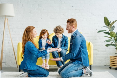 Parents playing game while children sitting on sofaの写真素材