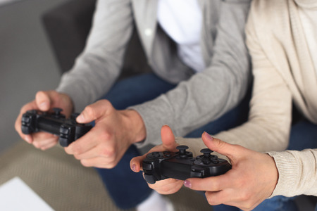 Cropped image of young couple holding game-pads at home