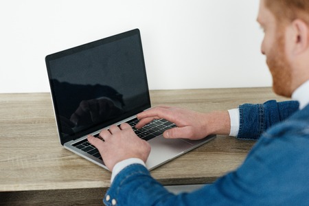 Redhead man typing on laptop keyboardの写真素材