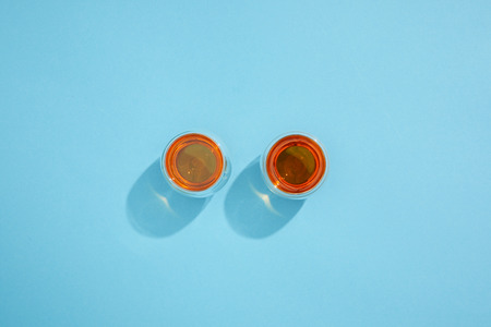 Top view of cups with fresh hot tea and shadows on blue background