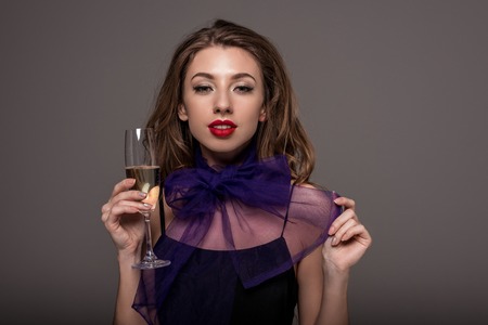 Attractive girl posing with champagne glass, isolated on grey backgroundの写真素材