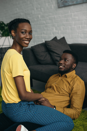 Happy young African American couple in love spending time together at homeの写真素材