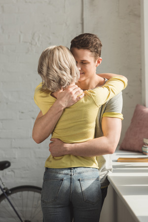 Affectionate couple standing and hugging at homeの写真素材