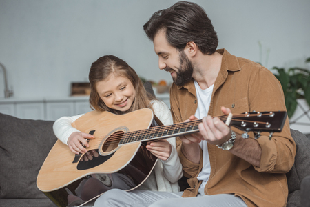 Happy father teaching daughter playing acoustic guitarの写真素材