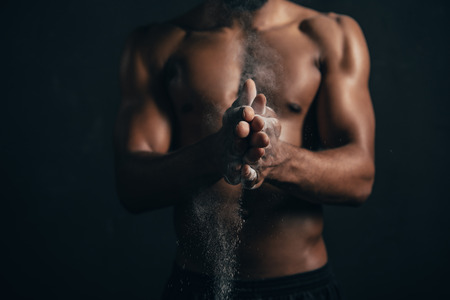 Cropped shot of African American sportsman applying talcum powder on hands on black backgroundの写真素材