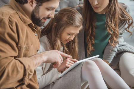 Cropped image of parents and daughter using tablet