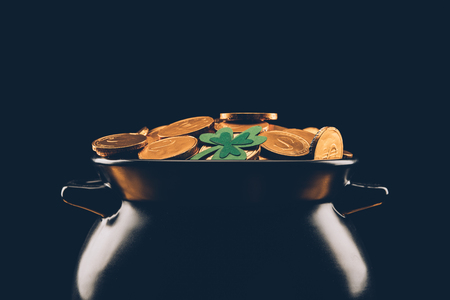 Black pot with golden coins isolated on black background, St Patrick's day conceptの写真素材