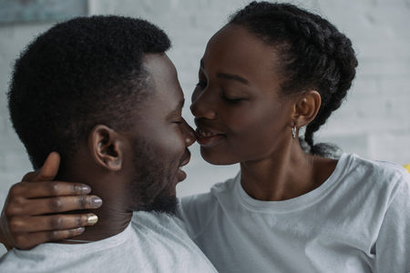 Beautiful happy young African American couple able to kiss at homeの写真素材