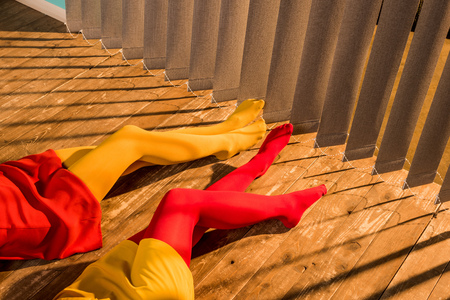 Cropped image of girls in colorful tights and dresses lying on floor near jalousieの写真素材