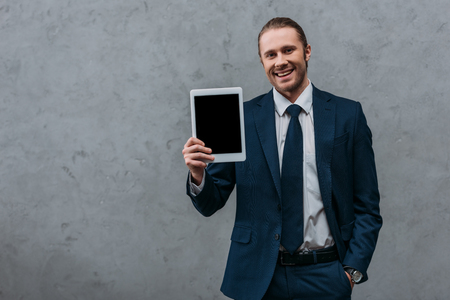 Young smiling businessman showing digital tablet at cameraの写真素材