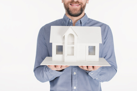 Cropped shot of bearded man holding house model in hands isolated on white backgroundの写真素材