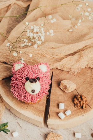 Top view of sweet pink muffin in shape of bear and nuts with sugar on wooden boardの写真素材