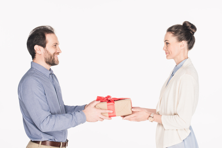 Side view of smiling man presenting wrapped gift to wife isolated on white backgroundの写真素材