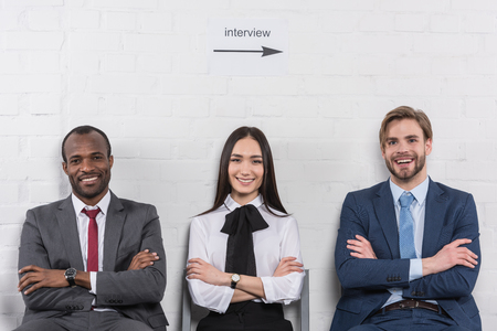 Portrait of smiling multicultural business people with arms crossed waiting for job interviewの写真素材